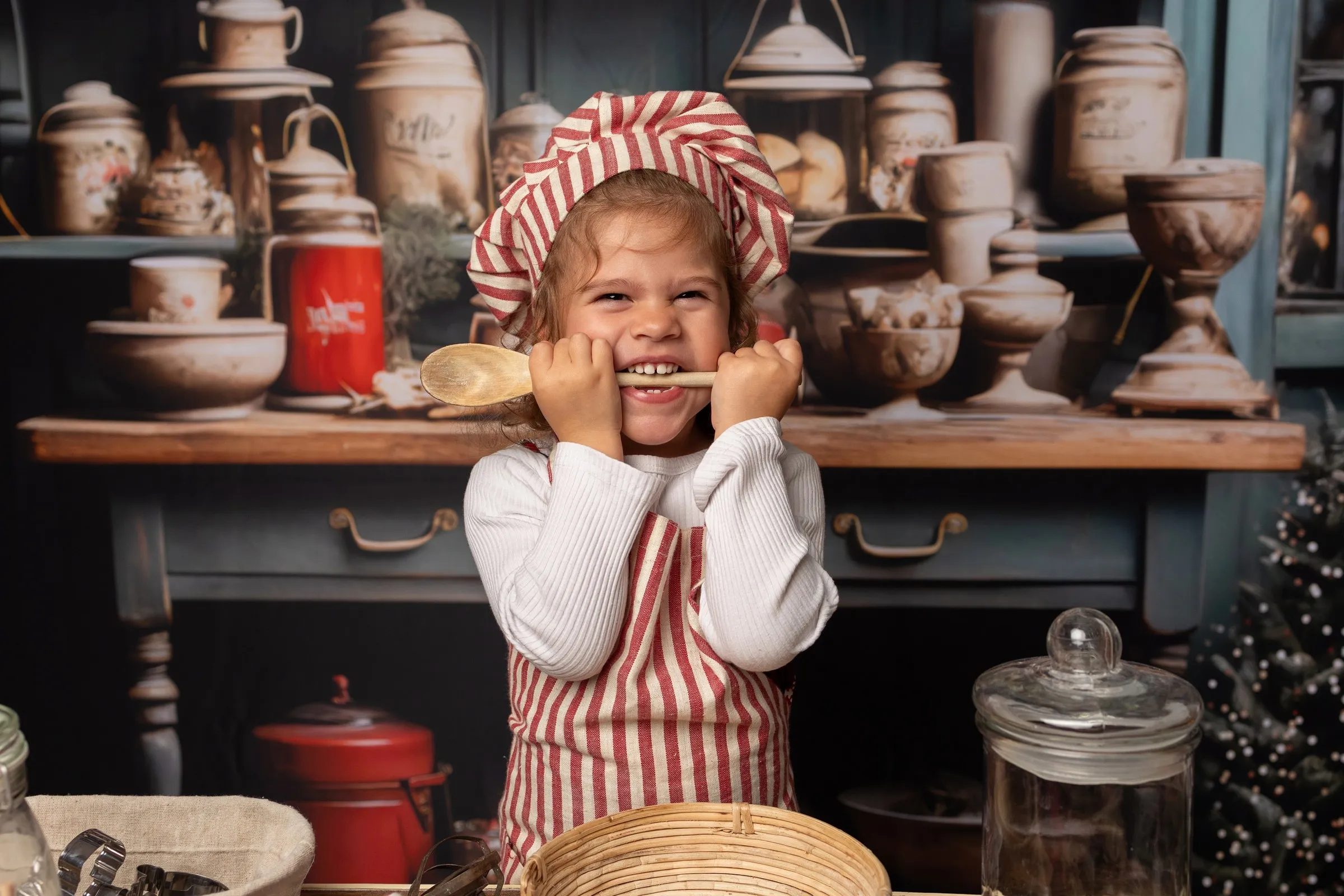 Enfant qui joue avec une cuillère en bois dans le décor cuisine de Noël, mini séance au studio