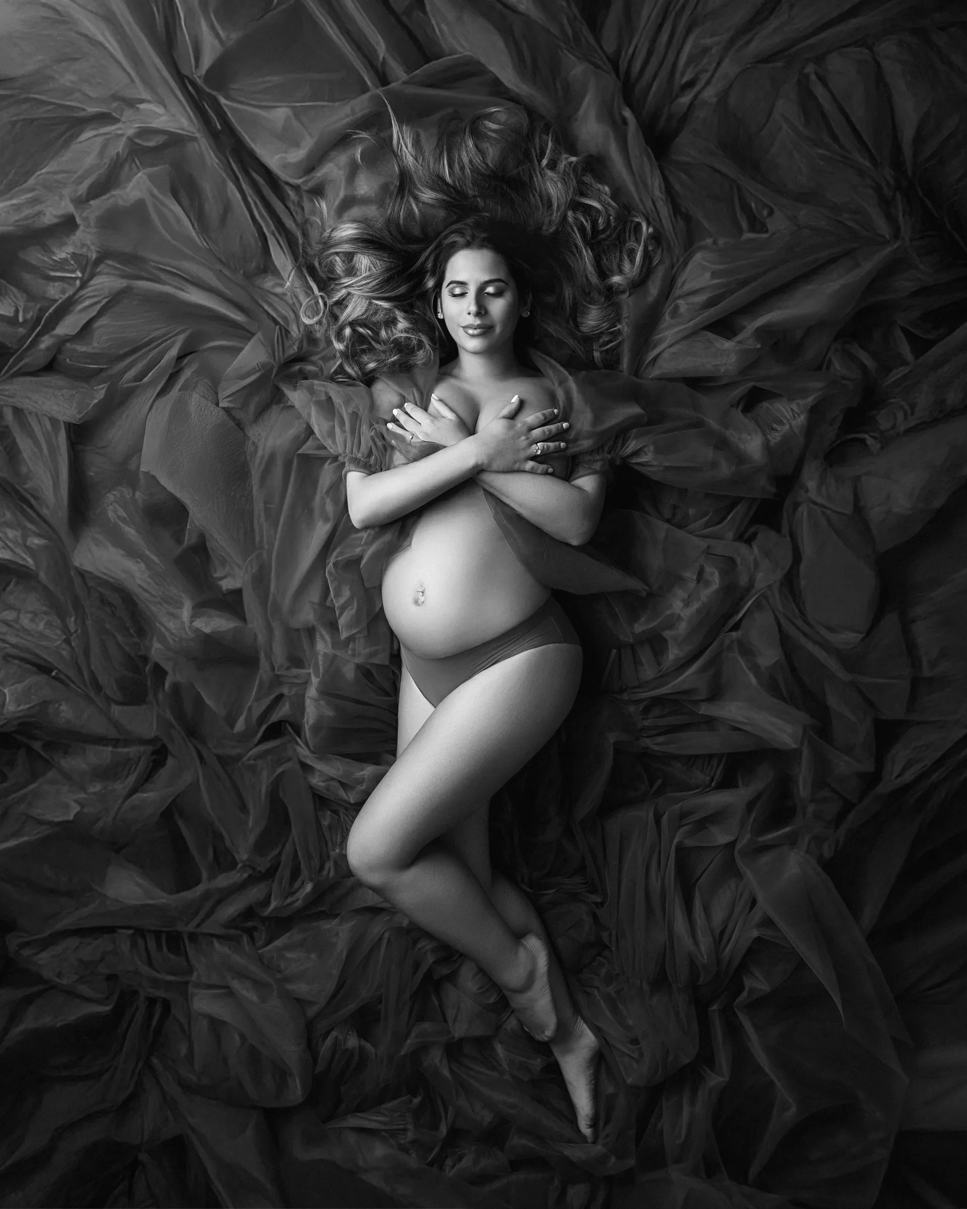 Portrait de grossesse en noir et blanc sur un drapé, vue de dessus