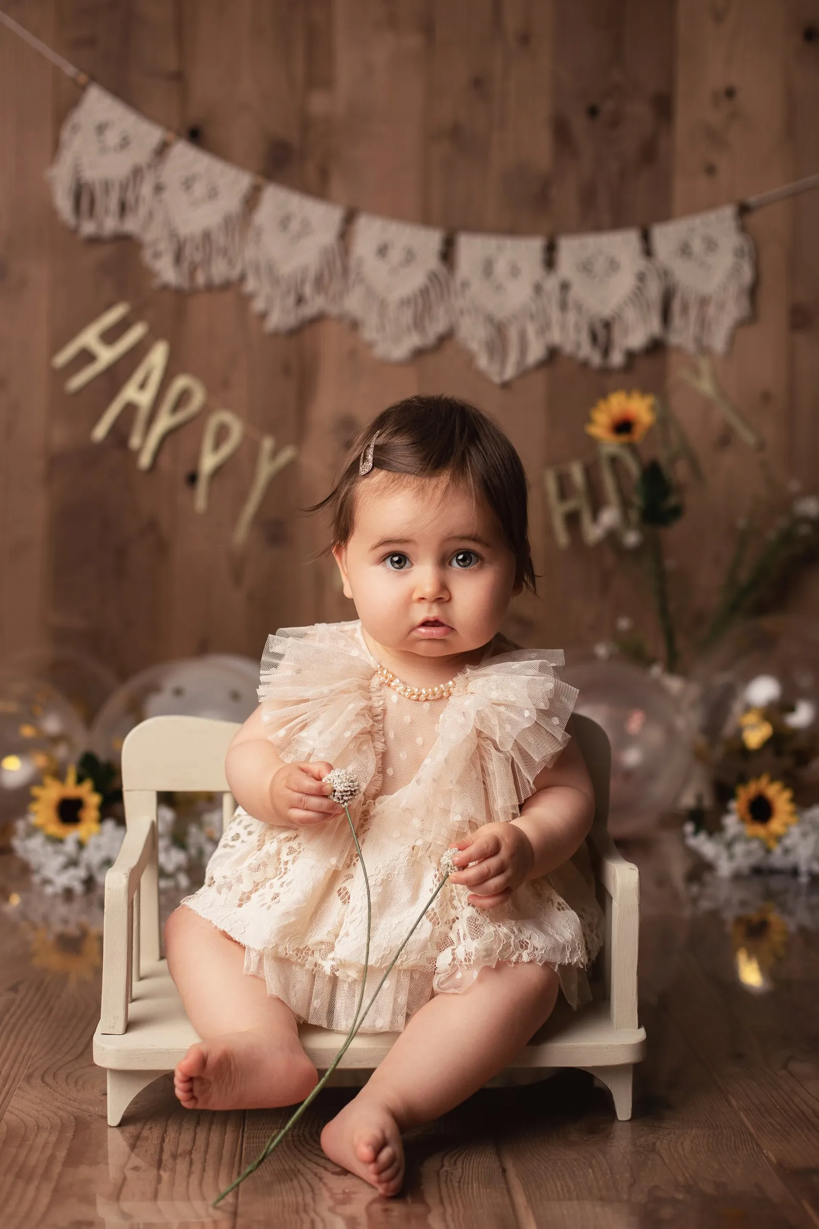Bébé d'un an assise dans un décor de tournesols, séance bébé en studio près de Toulouse