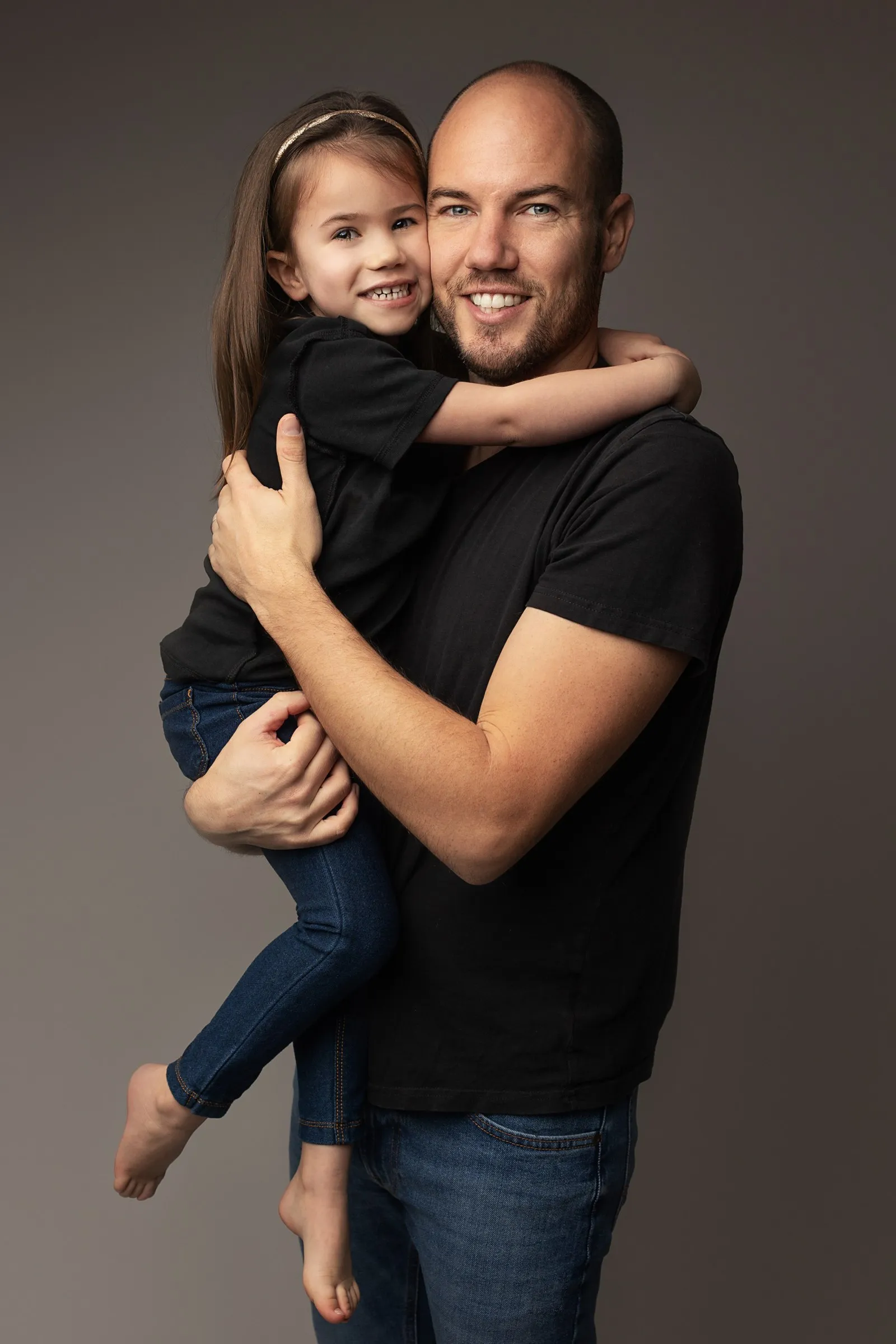Papa et sa fille complices dans les bras, séance photo famille en studio