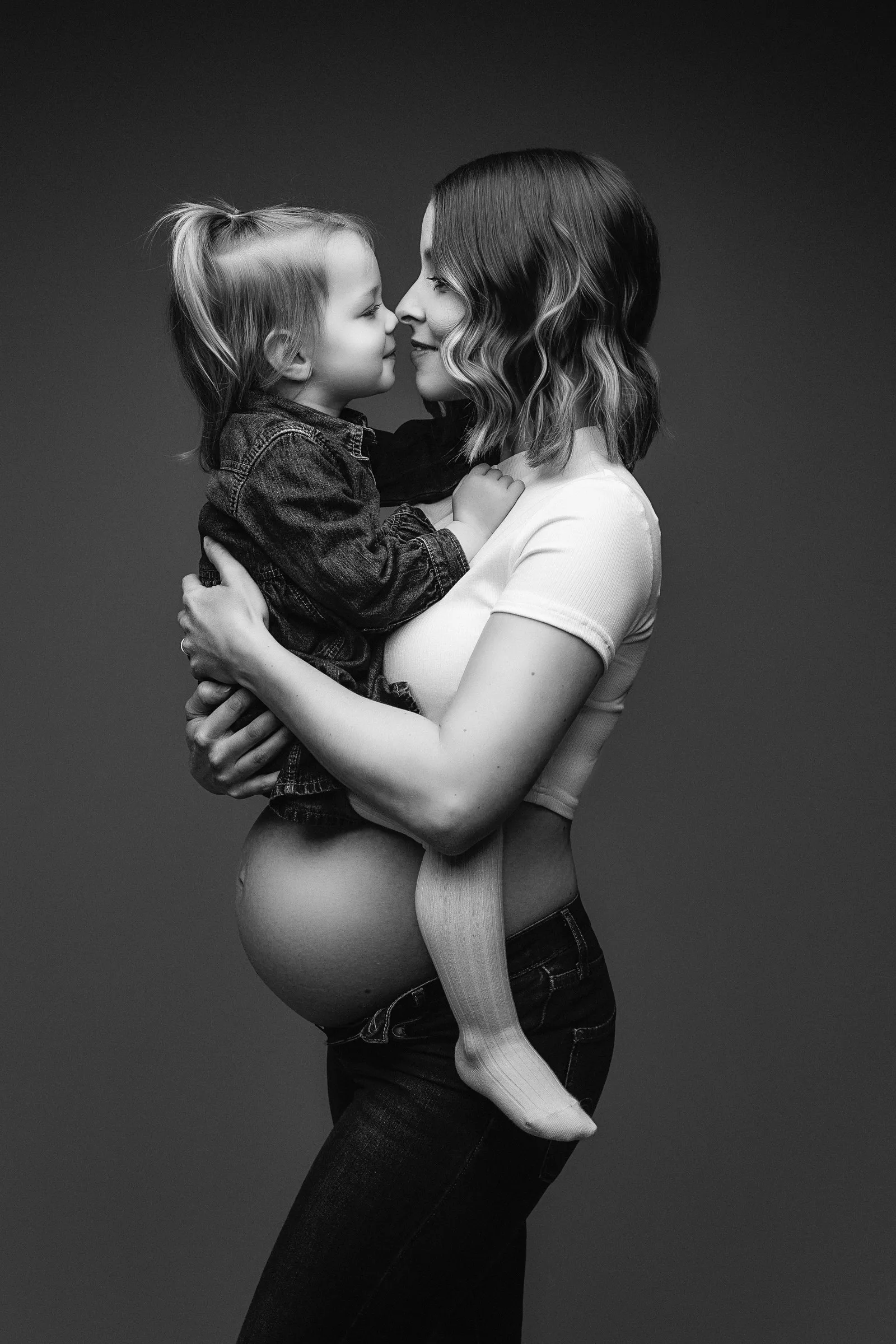 Maman enceinte portant son aîné, séance grossesse en noir et blanc en studio