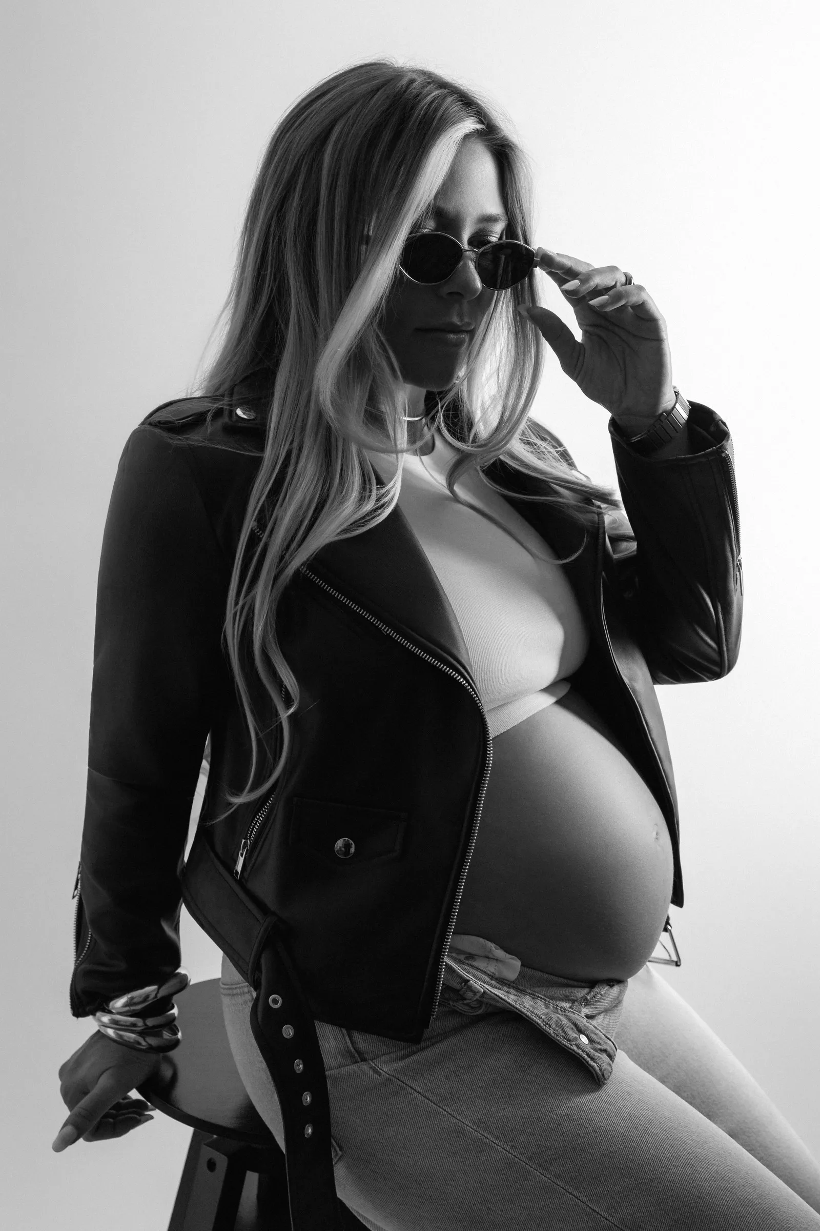Portrait de grossesse en noir et blanc, perfecto en cuir et lunettes de soleil, séance en studio près de Toulouse