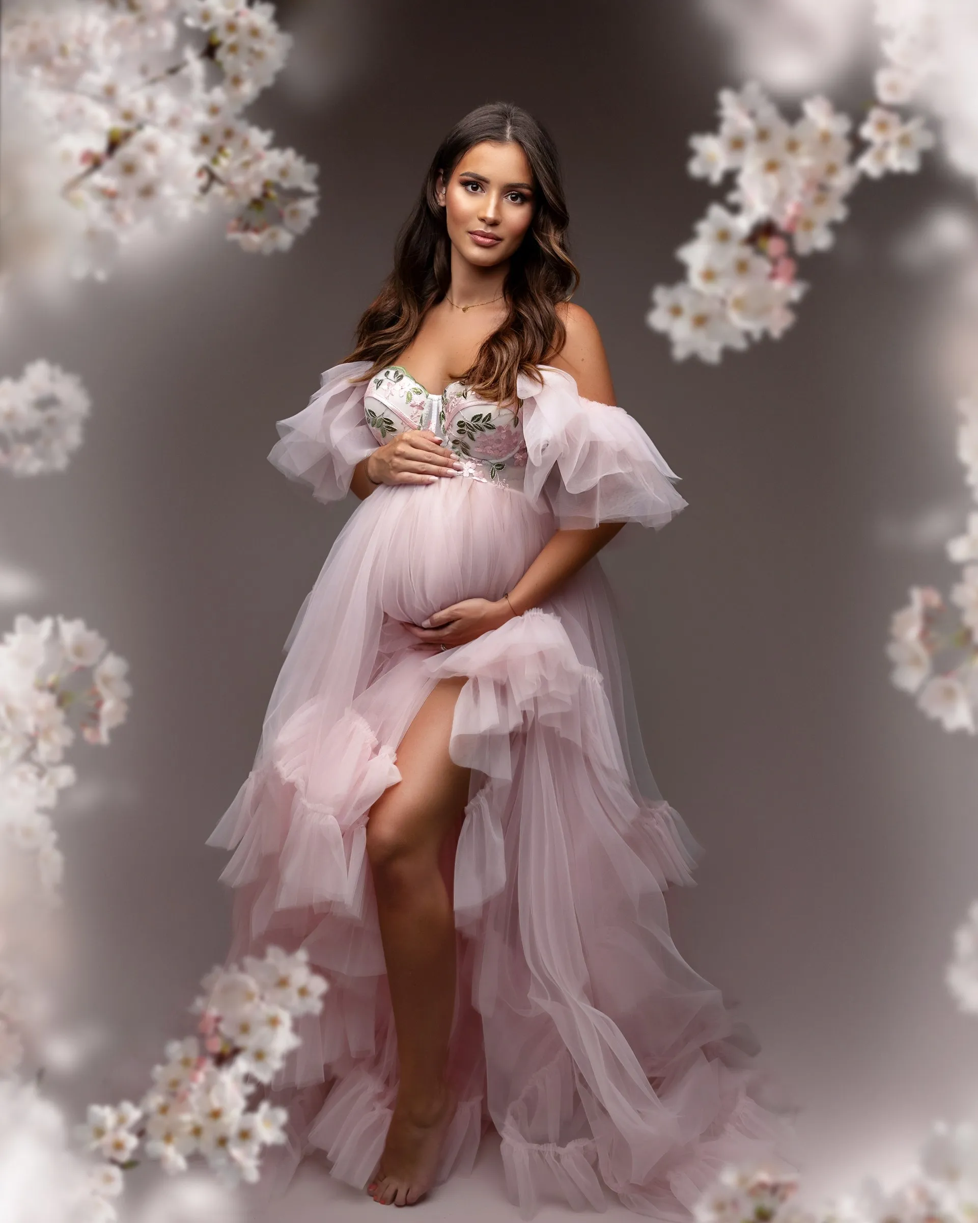 Future maman en robe rose sous des fleurs de cerisier, séance grossesse en studio