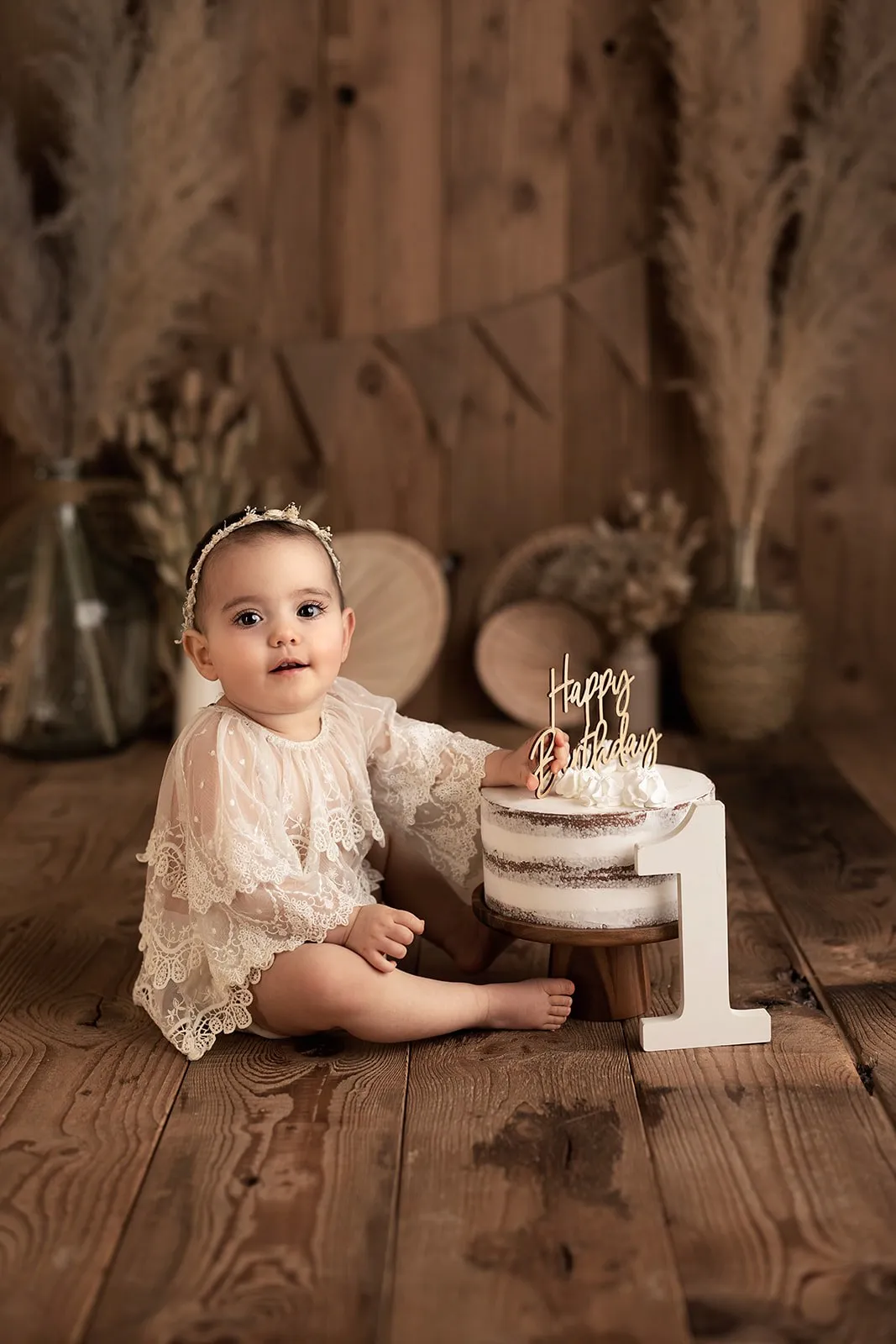 Bébé qui découvre son gâteau d'anniversaire, séance smash cake décor bohème