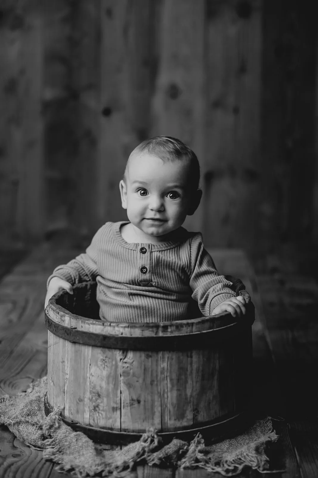 Bébé assis dans un seau en bois, portrait noir et blanc en studio, Emilie Colusso photographe