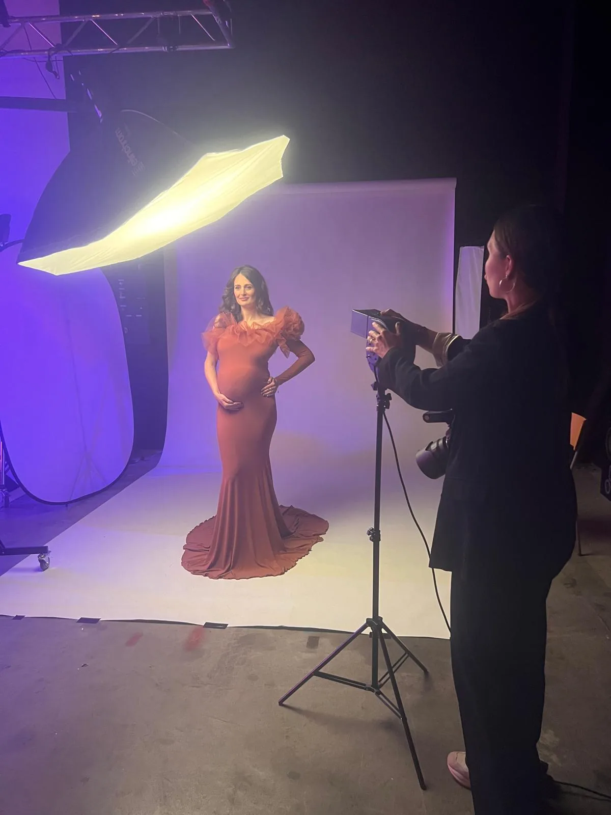 Stagiaire au boîtier photographiant une modèle en robe rouge, formation grossesse à Toulouse